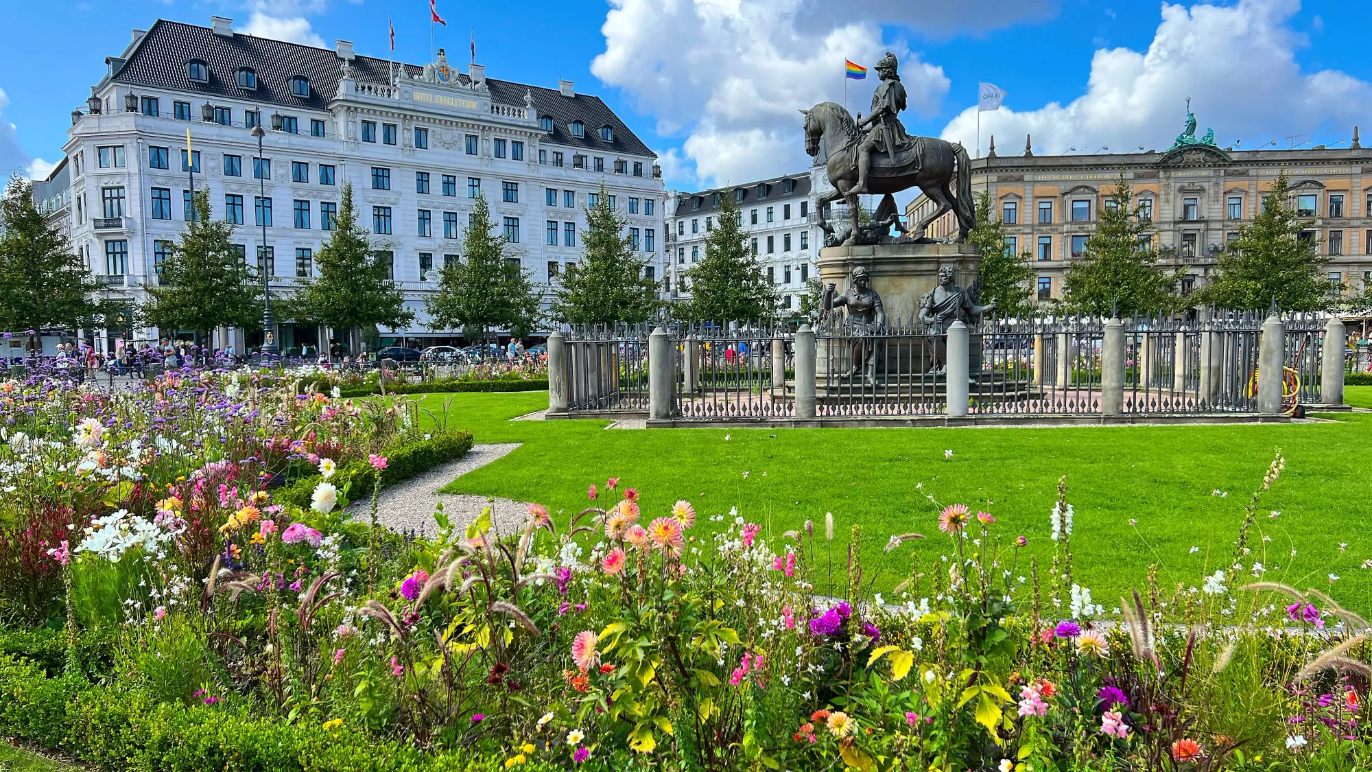 Assortment of pink and purple flowers in front of a statue of a mounted rider