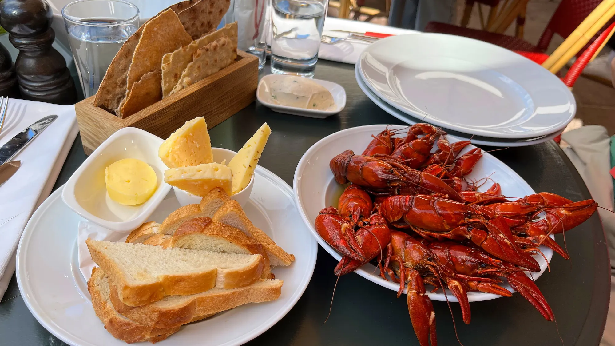 Table set with bread, butter, cheese, crackers, and a bowl of crayfish