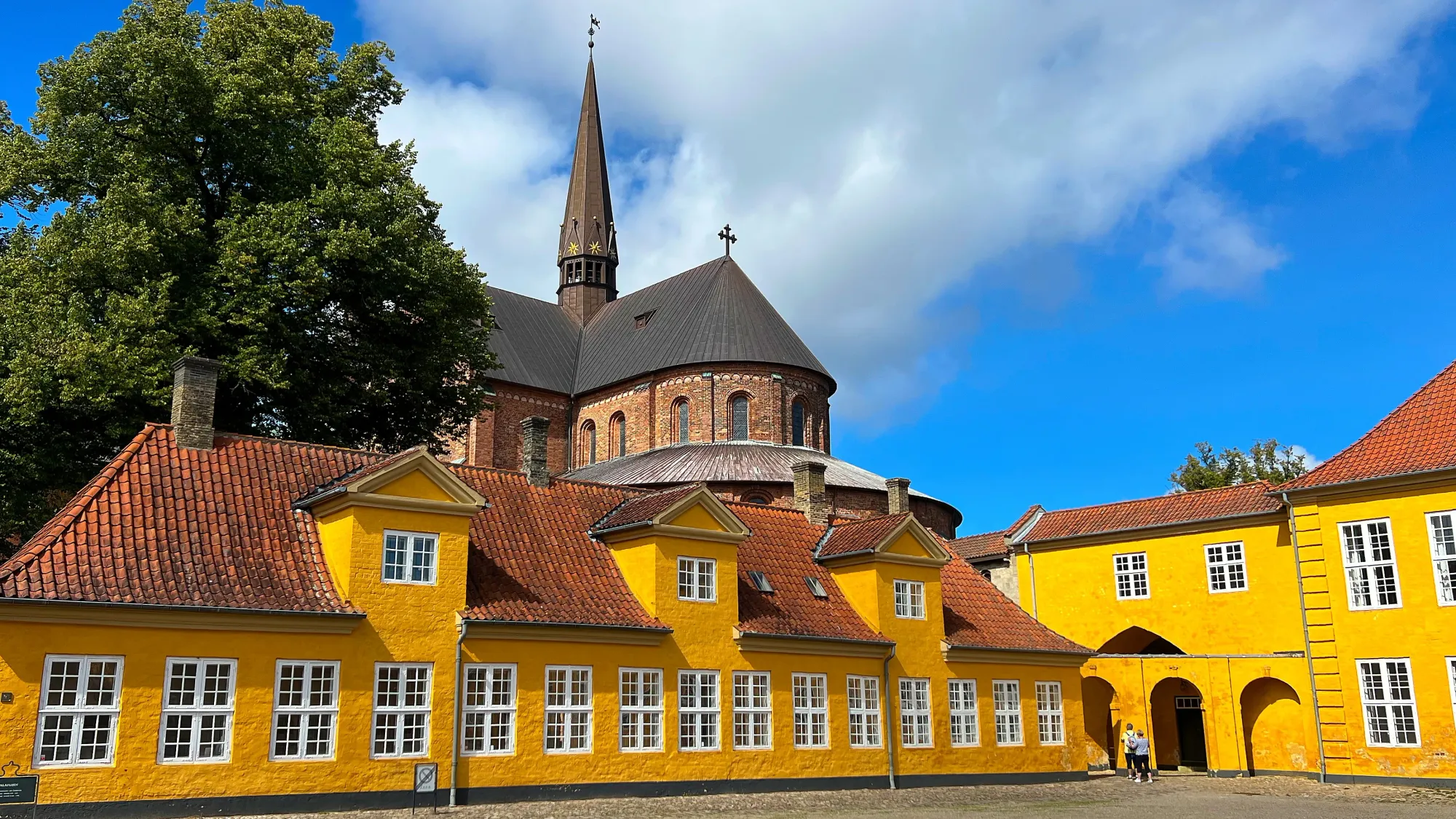 Yellow Mansion with a church steeple in the background