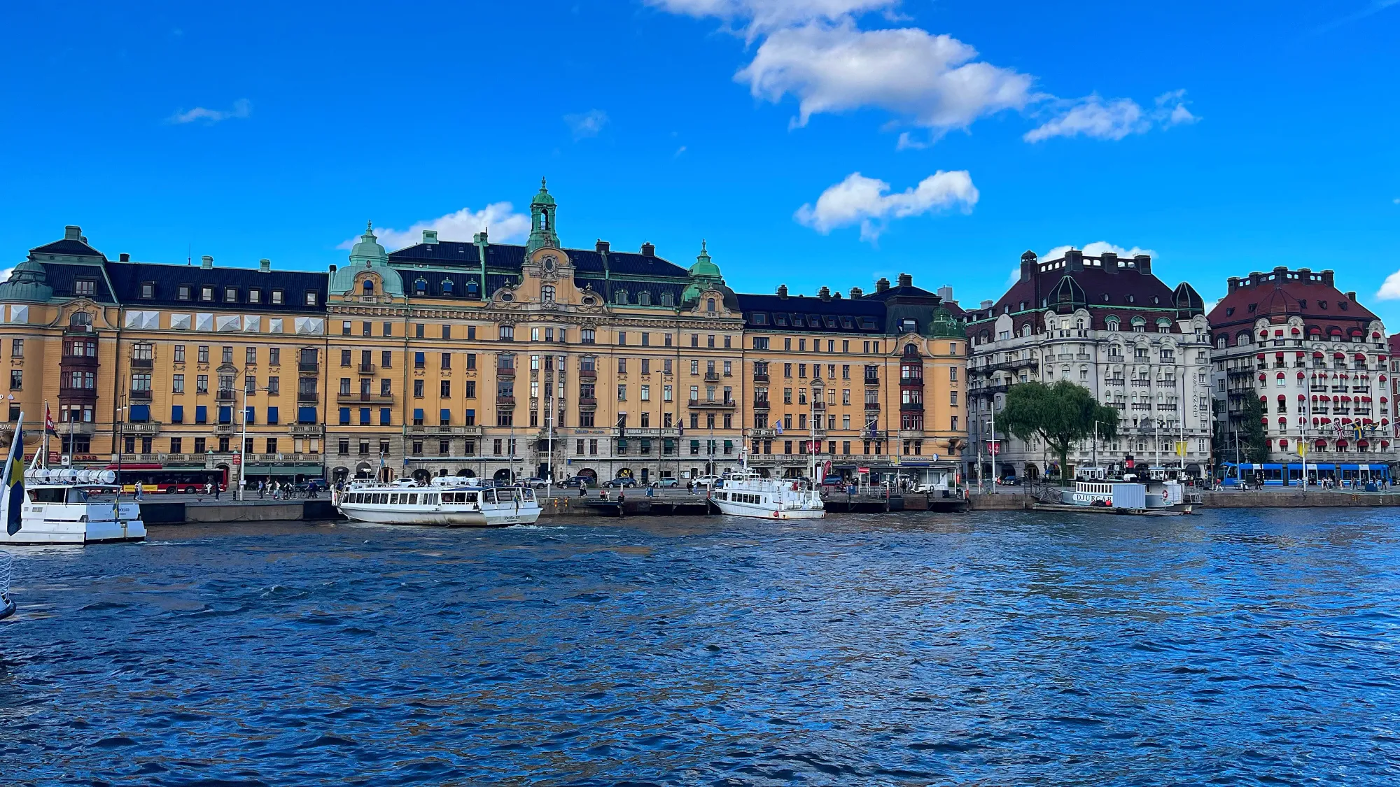 Blue harbor water with yellow Swedish building and white boats