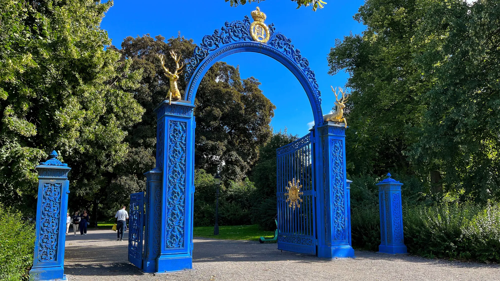 Blue gate with golden stags open to a public park