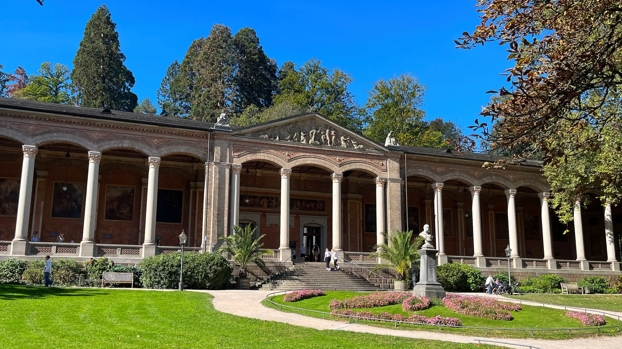 One story building with a row of columns lining the porch and a bust out front