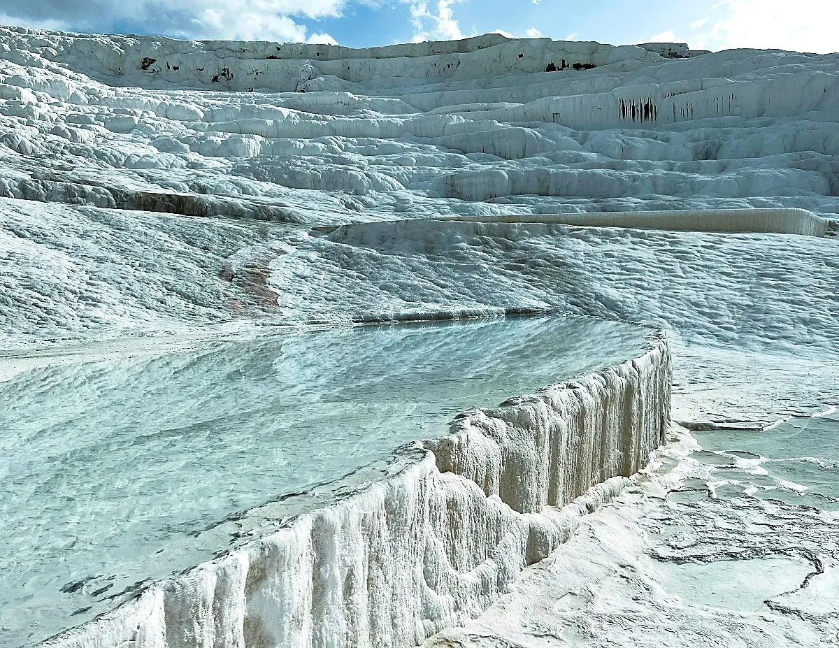 A singular filled calcite pool reflecting its surroundings