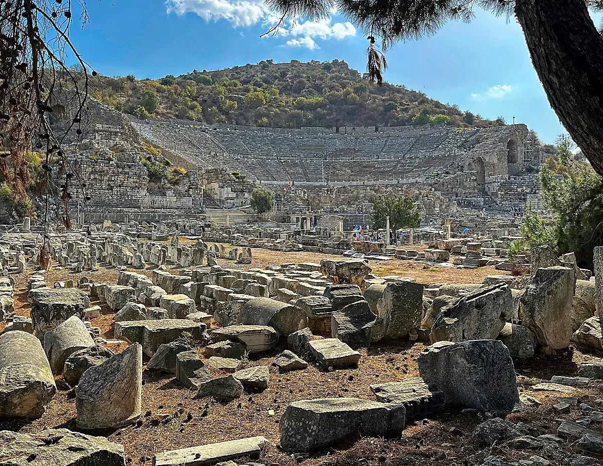 Disassembled rubble in the foreground with the great theater set into the hillside in the background