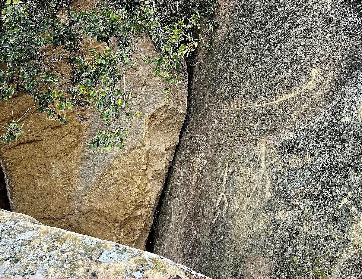 Sandstone rocks with carvings of people and a boat etched in them