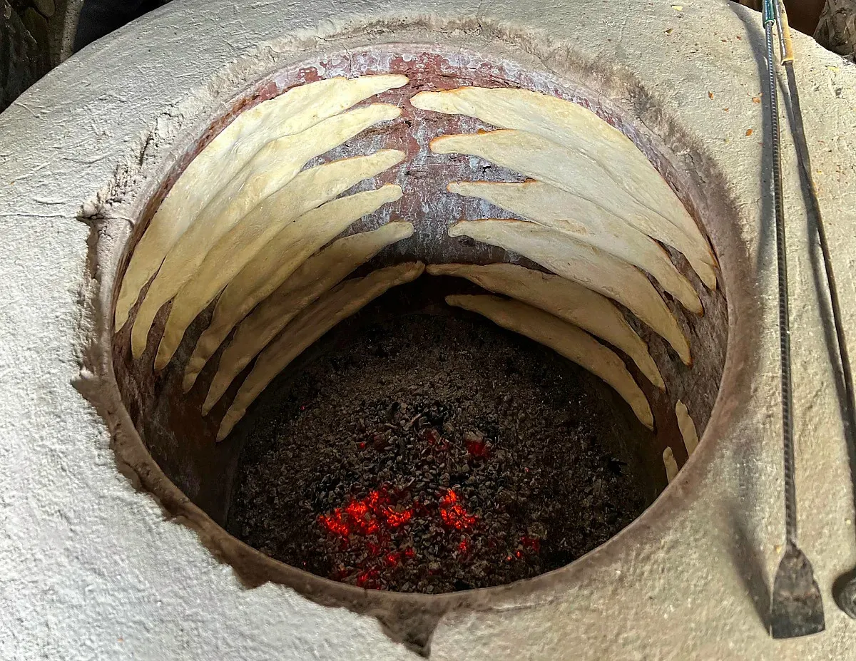 Fresh baking boat-shaped bread in a round clay oven