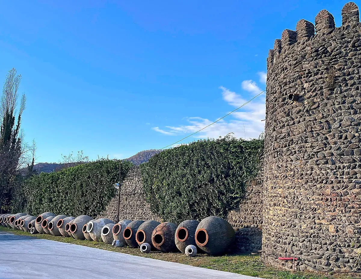 A stone wall lined with giant clay jugs that used to house wine