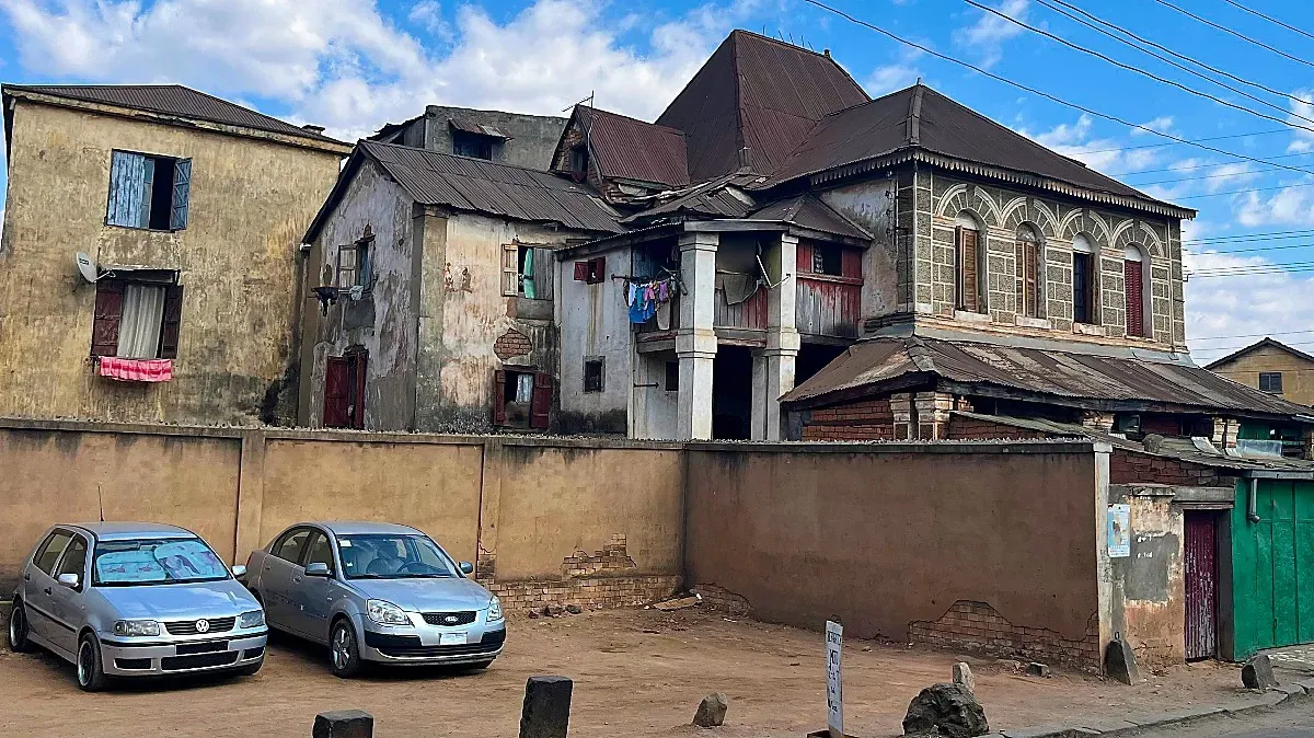 Stone and columned home, now dilapidated and covered in peeling paint and drying clothes