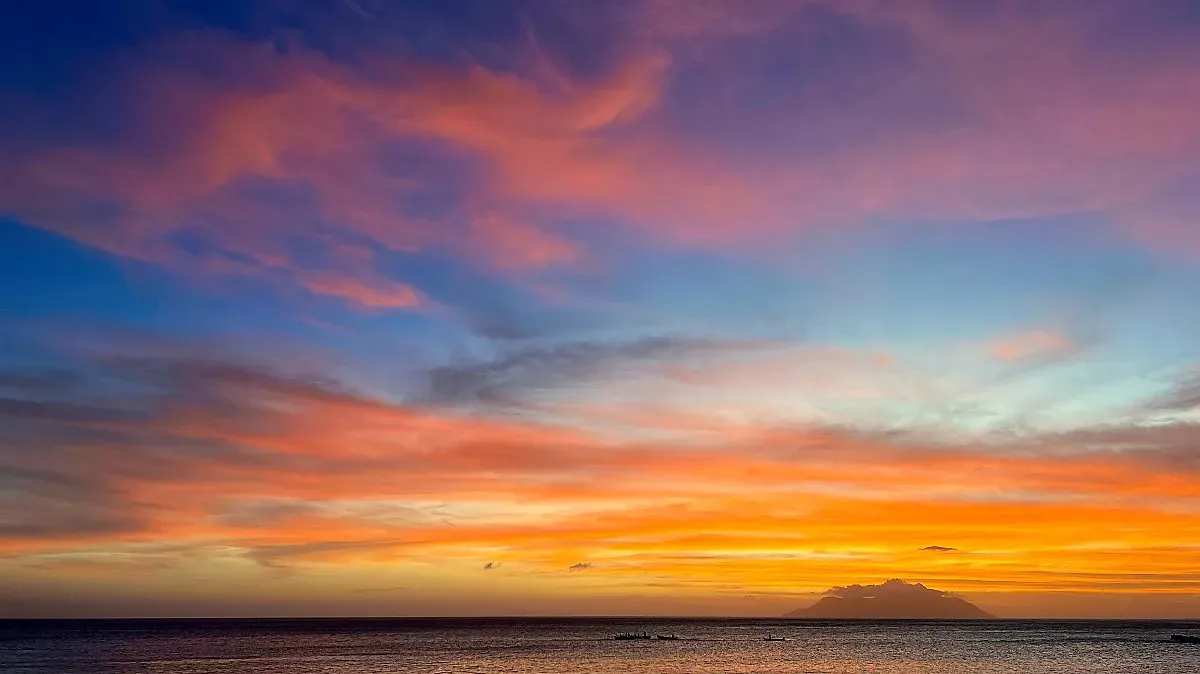 Pink, blue, orange, and yellow sunset over a narrow strip of water