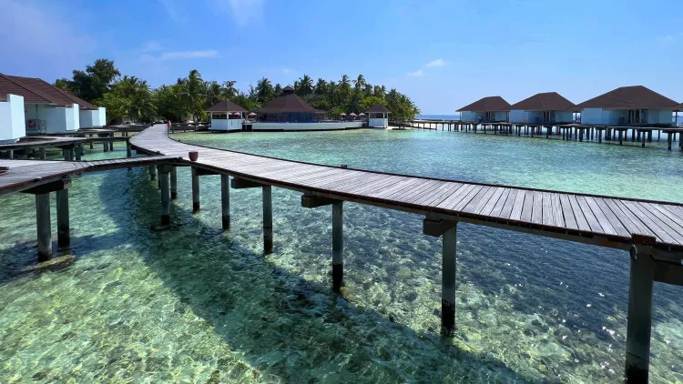 White bungalows over shallow blue-green water with a reef in the center