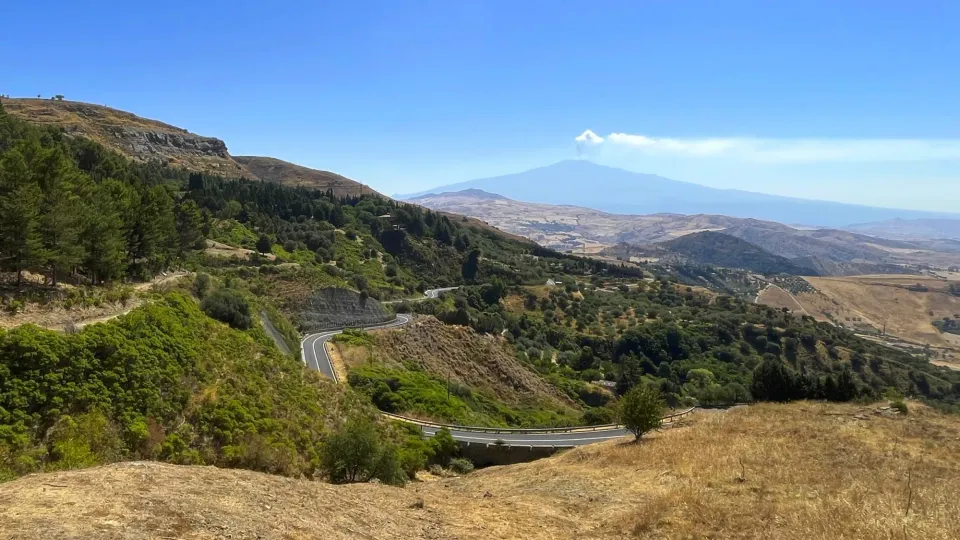Winding road through Sicily countryside with Mt. Etna in background. Landscape shot.