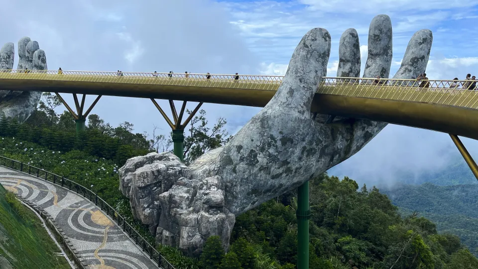 Golden Bridge supported by two stone hands looking down over the valley through the mist