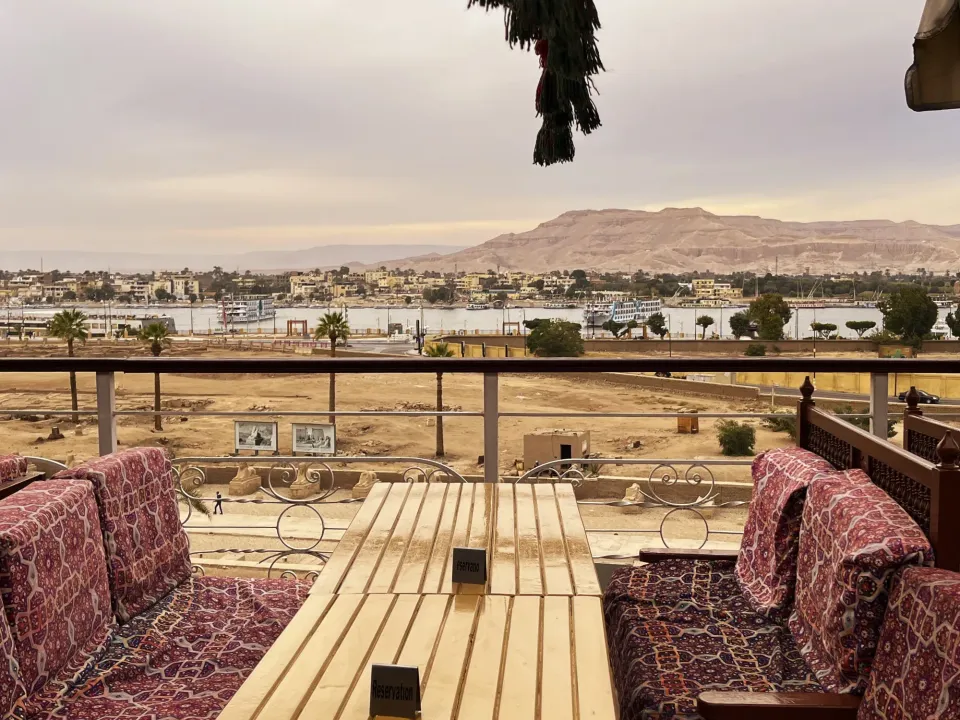 Dining table on a rooftop restaurant overlooking the Nile with the Valley of the Kings in the backgroun