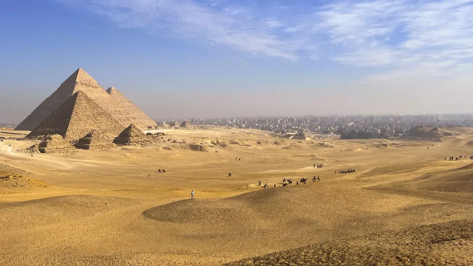 Sandy landscape overlooking the Great Pyramids of Giza with the city in the background