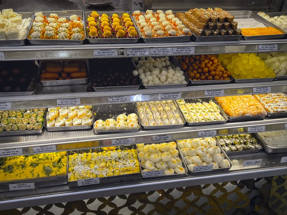 Photo of a counter full of sweets at a Bengali sweet shop.