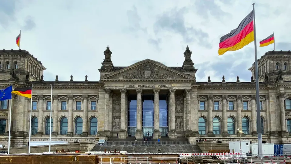 Grey stone Berlin parliament building with German and EU flags flying