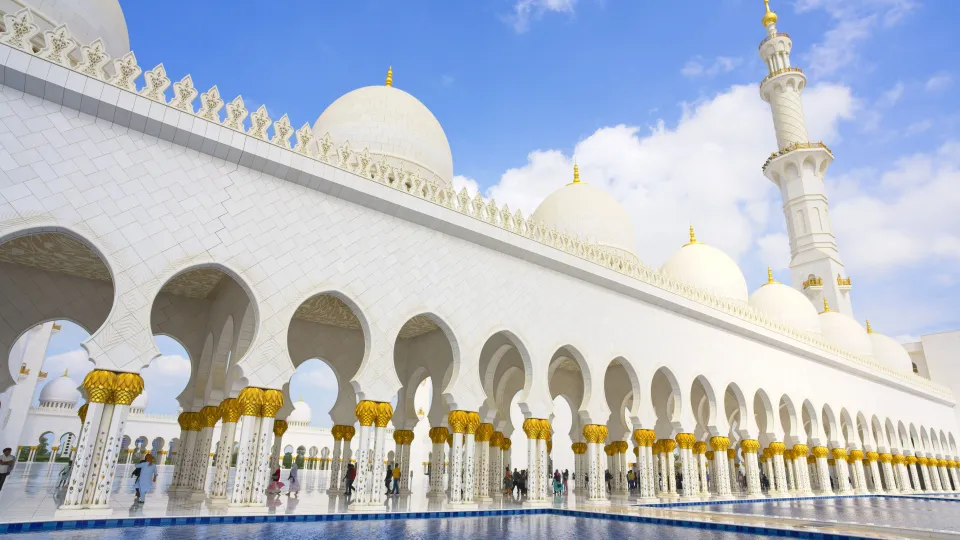 Side photo of the Sheikh Zayed Grand Mosque with white and gold columns and domes