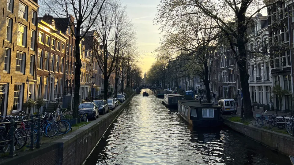 Canal at sunset lined with houseboats and bikes